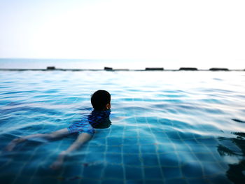 Boy lying in infinity pool