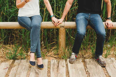 Low section of couple sitting on wood