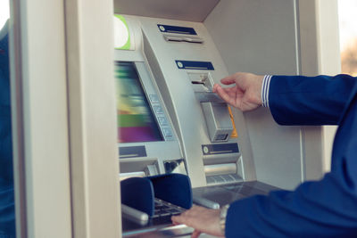 Midsection of man using atm machine