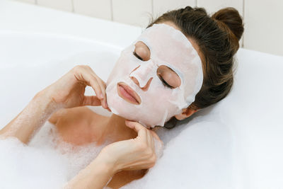 Woman with sheet mask taking bath