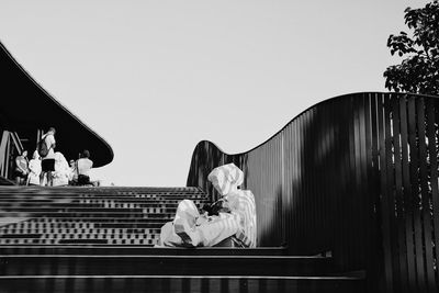 Couple sitting against clear sky