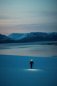 A man backcountry skiing at sunrise with mountains and ocean