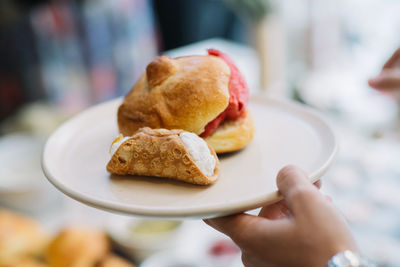 Close-up of hand holding ice cream in plate