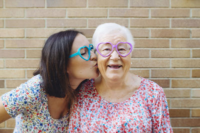 Happy granddaughter and grandmother wearing heart-shaped glasses