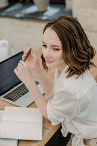 High angle view of woman using phone while sitting on table