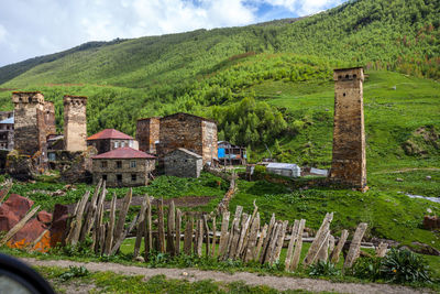 Houses on field by mountain against sky