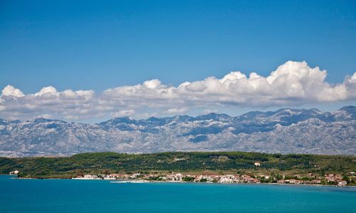 Scenic view of sea and mountains against blue sky