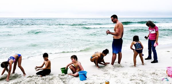 People playing at beach against sky