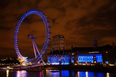 Illuminated ferris wheel in city at night