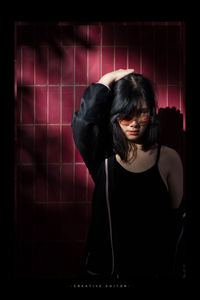 Portrait of young woman standing against wall