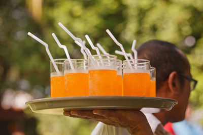 Close-up of waiter carrying fresh drinks in tray