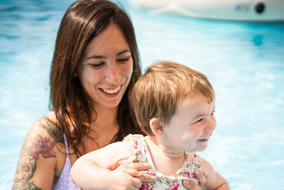 Woman in the middle of the pool holding a little girl who is smiling