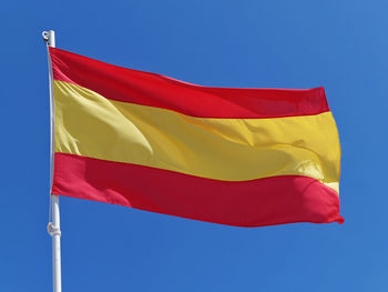 Low angle view of spanish flag against clear blue sky