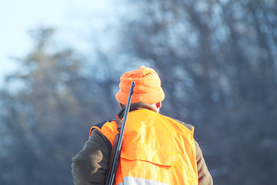 Rear view of man with rifle against trees