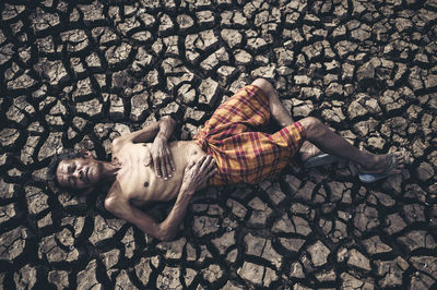 Full length of senior man with lying on cracked land