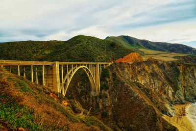 Arch bridge over mountains against sky