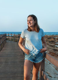 Portrait of young woman standing against sea