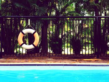 Life belt hanging on fence by swimming pool