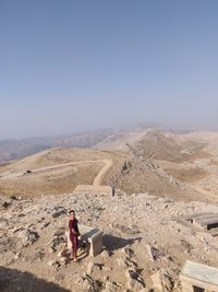 High angle view of man standing on mountain against clear sky