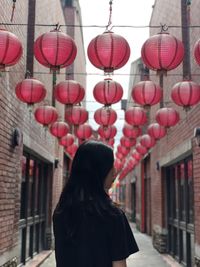 Rear view of woman standing by lanterns in city