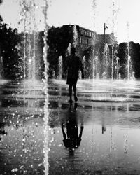 Silhouette man standing on puddle in city