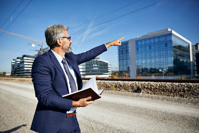 Man standing by building against sky in city