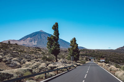 Road by mountains against clear blue sky