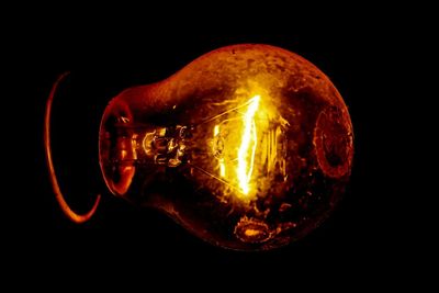 Close-up of illuminated light bulb against black background