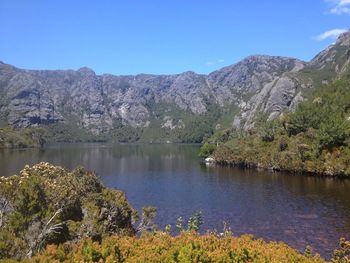 Scenic view of lake and mountains against clear blue sky