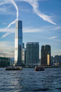 Sea by modern buildings against sky in city