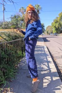 Young man wearing blue sweater and pants with orange hat and socks posing outside 