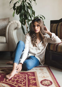 Portrait of young woman sitting on sofa at home