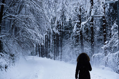 Rear view of woman standing on snow covered land