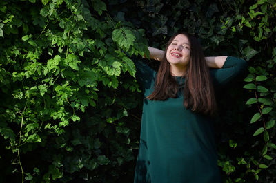 Portrait of smiling young woman standing against plants