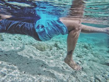 Low section of man swimming in sea