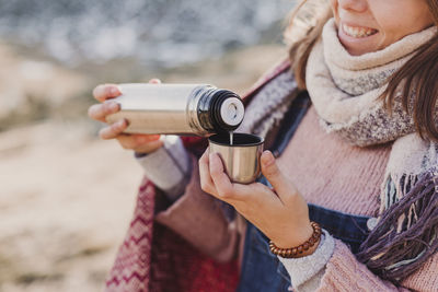 Midsection of woman pouring drink in bottle cap