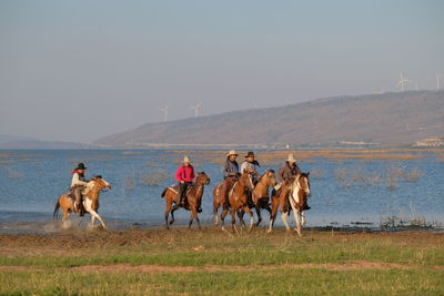 Group of people riding horses on field