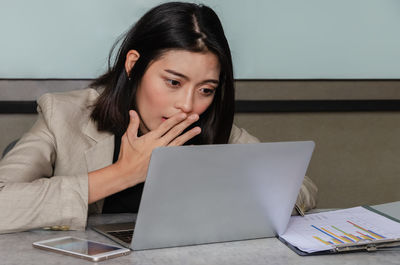 Portrait of young woman using phone while sitting on table