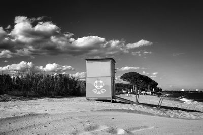 Information sign on beach against sky