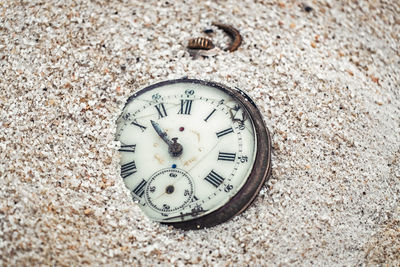 Sands of time, antique rotten pocket watch partial buried in the sand