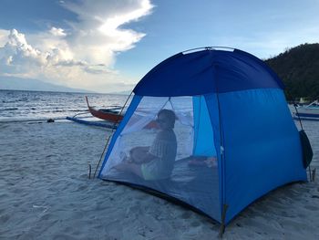 Woman sitting in tent at beach