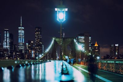 Illuminated lamppost on brooklyn bridge in city at night