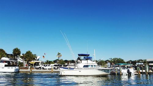 Boats moored in sea against clear blue sky