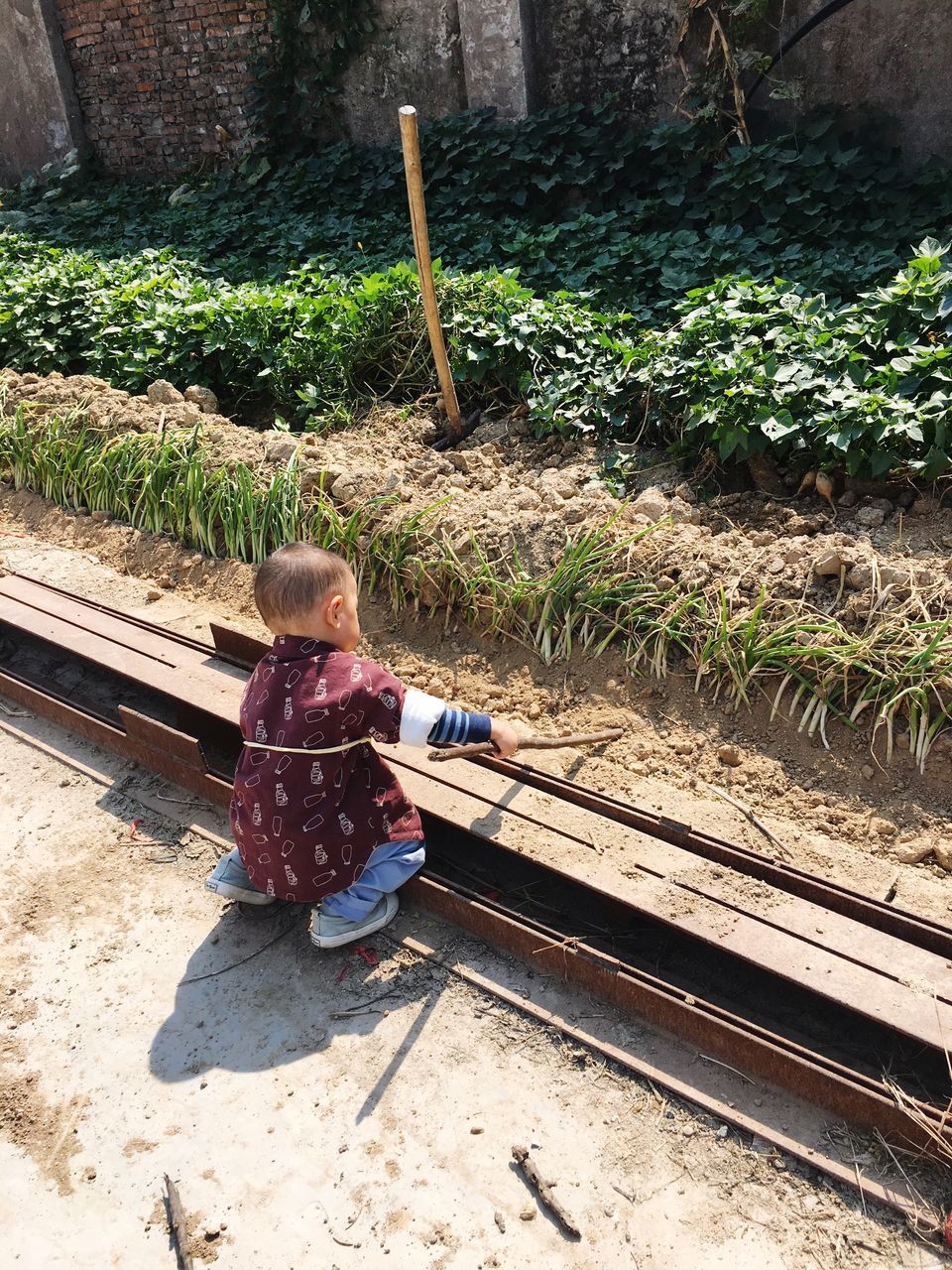 HIGH ANGLE VIEW OF GIRL SITTING BY RAILROAD TRACK