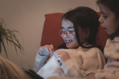 Two girls are watching a movie while sitting on the couch.