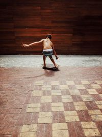 Full length of shirtless man on woman standing on footpath