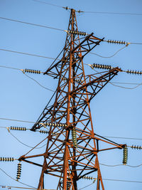 Low angle view of electricity pylon against clear blue sky