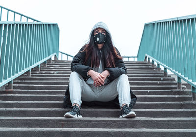 Full length portrait of woman sitting on staircase