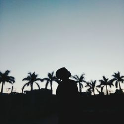 Silhouette man with palm trees against clear sky