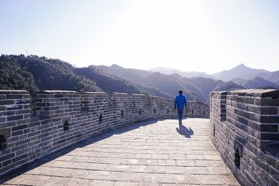 Man walking at great wall of china against sky